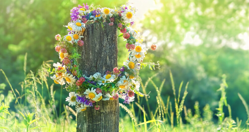 Wooden,Post,With,Flowers,Wreath,On,Sunny,Meadow.,Summer,Background.